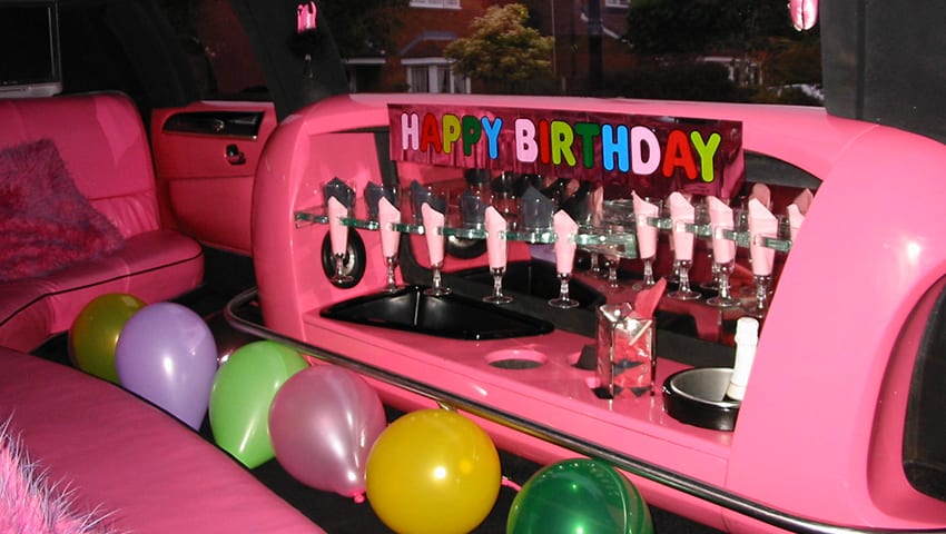 Pink stretch limo interior set for a birthday — Happy Birthday banner and balloons